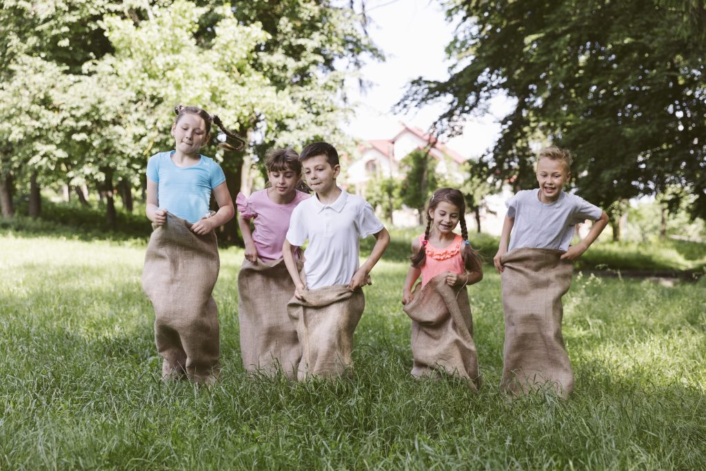 Participez à une course en sac amusante pour faire bouger les enfants lors de votre kermesse scolaire Enfants participant à une course en sac lors d’une kermesse scolaire en plein air