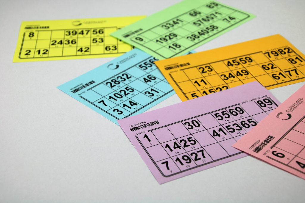 Les cartons de loto sont de plusieurs couleurs et sur un fond neutre Cartons de loto éparpillés.