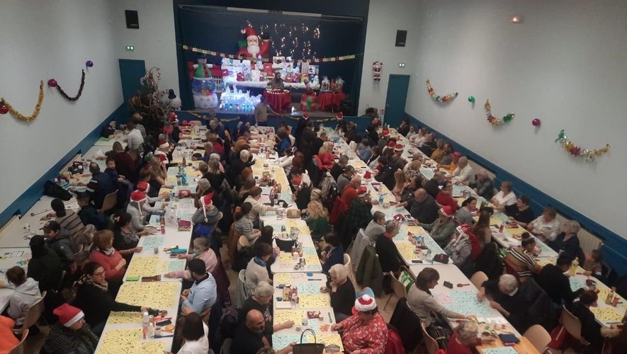 Loto de Noël dans une salle des fêtes décorée, réunissant de nombreux joueurs Grande salle des fêtes remplie de participants lors d’un loto de Noël, tables alignées et décorations festives