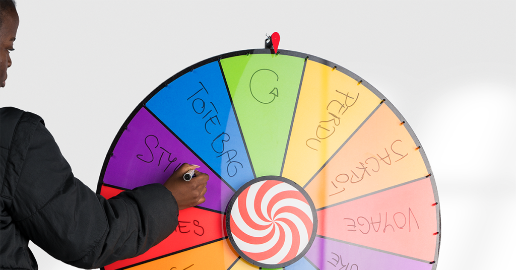 Une personne écrit avec un marqueur sur les sections colorées d'une grande roue de fortune effaçable.